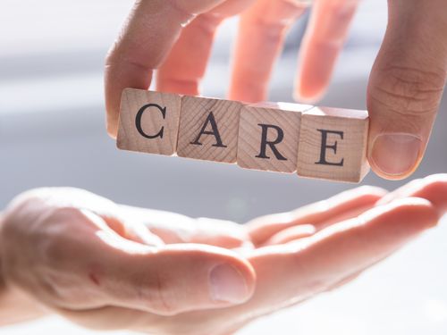 Hand holding wooden blocks spelling care